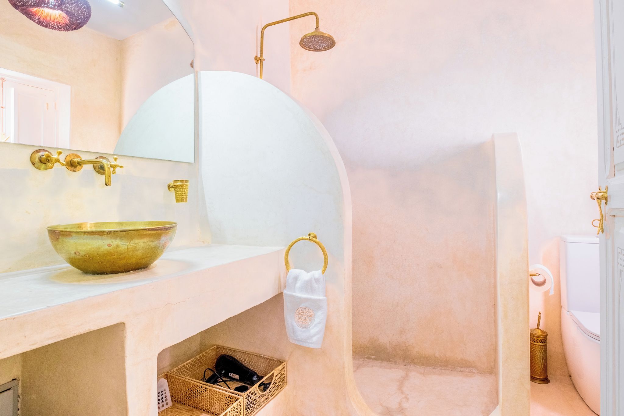 Ein Badezimmer mit einem weißen Waschbecken, goldenen Armaturen und einer Duschkabine.