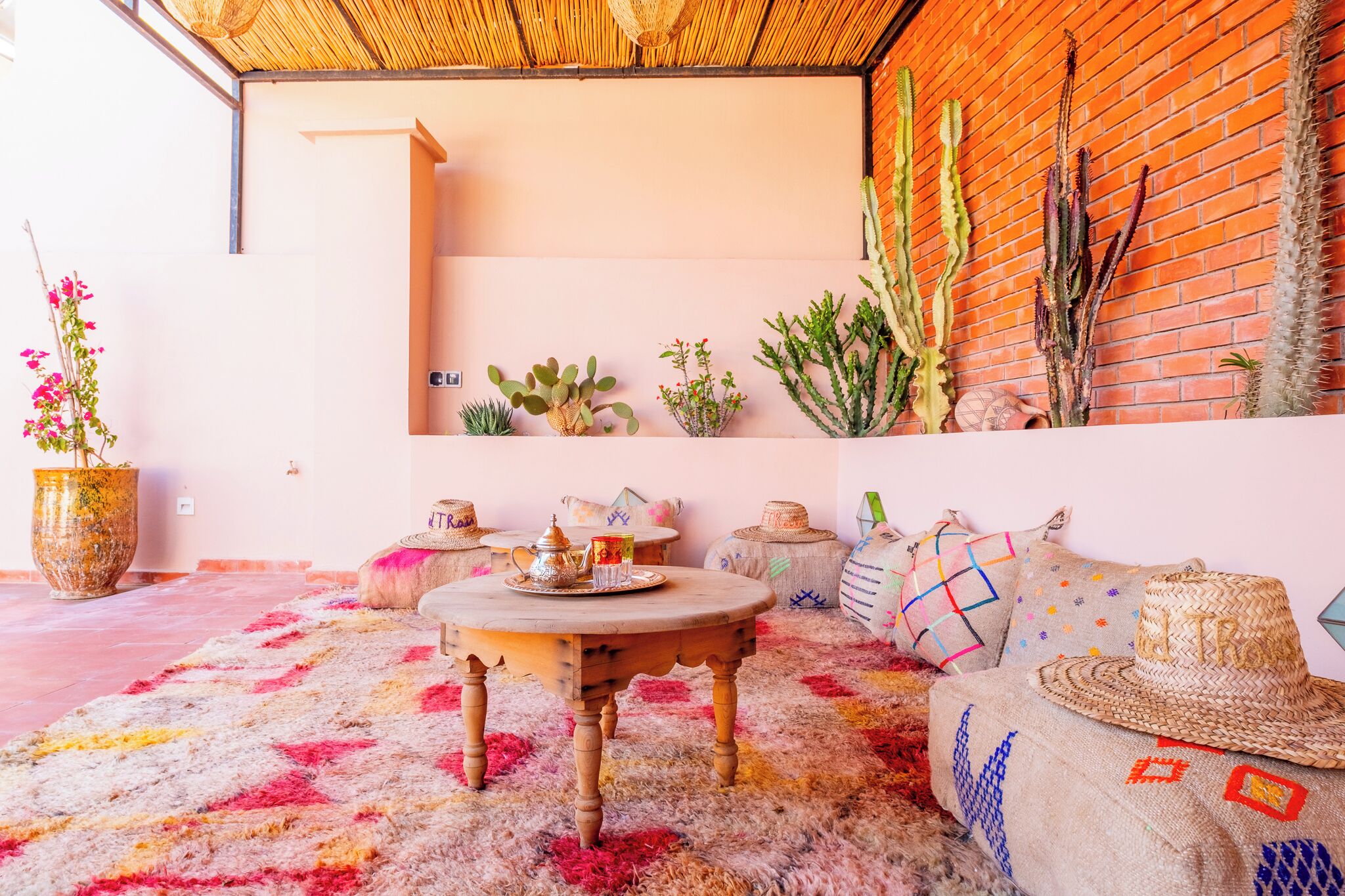 A cozy interior with a round wooden table, a brick wall, and various plants.