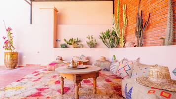 A cozy interior with a round wooden table, a brick wall, and various plants.