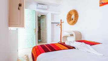 A hotel room with a bed, a headboard, a wall-mounted towel rack, and a door leading to a bathroom.