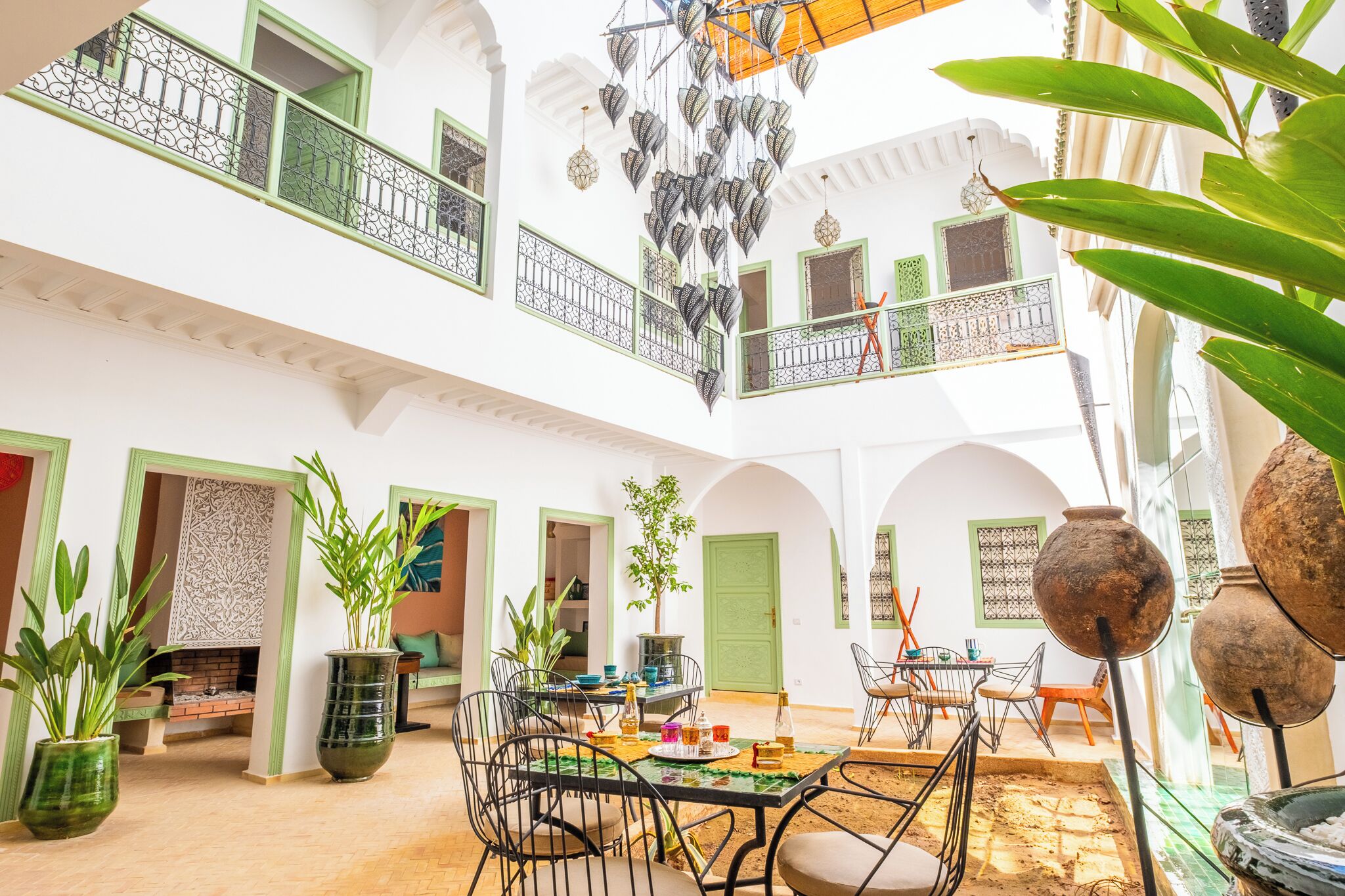 Un intérieur spacieux comprenant un coin repas, plusieurs portes et un balcon agrémenté de lampes décoratives suspendues.