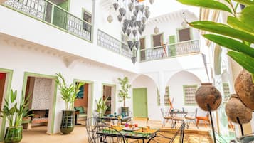 A spacious interior with a dining area, multiple doors, and a balcony with decorative hanging lamps.