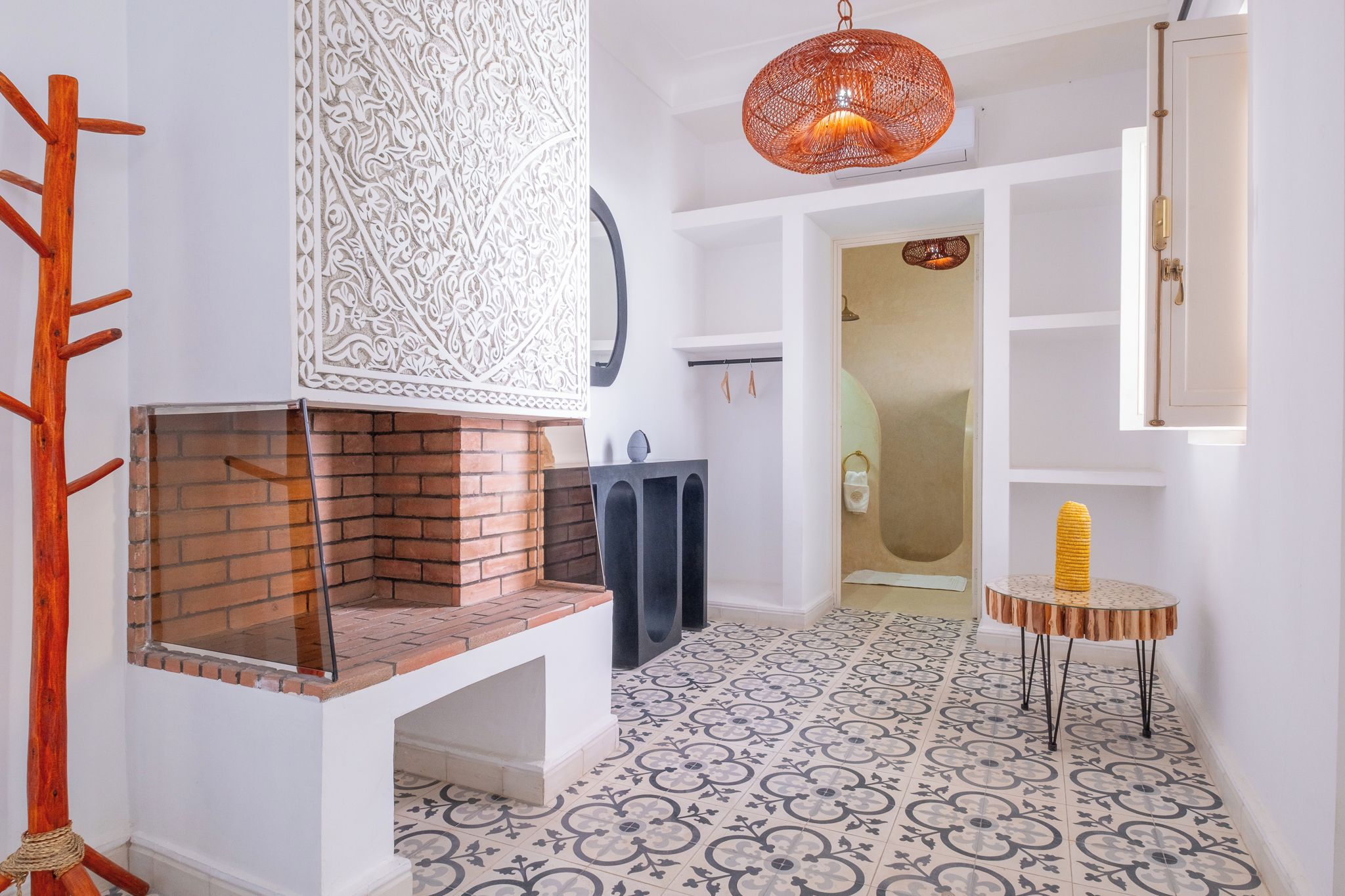 Ein modernes Interieur mit Kamin aus Ziegelsteinen, gemustertem Boden und einer außergewöhnlichen Pendelleuchte.
