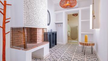 Ein modernes Interieur mit Kamin aus Ziegelsteinen, gemustertem Boden und einer außergewöhnlichen Pendelleuchte.