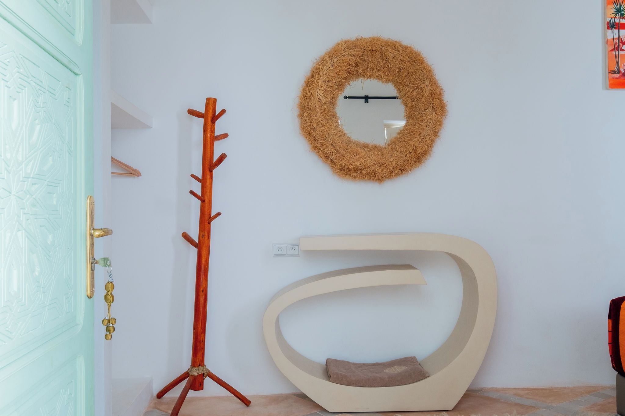A room with a coat rack, a mirror, and a unique curved seating area.