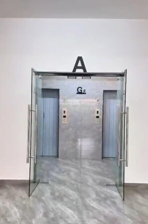 An elevator with a metallic finish, a glass door, and a sign with the letter 'A' above it. - Peaceful and central apartment with fitness room for a relaxing stay. (Nairobi)