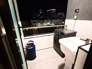 A small balcony with a washing machine, a sink, and a blue gas cylinder. - Peaceful and central apartment with fitness room for a relaxing stay. (Nairobi)