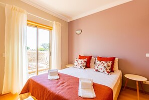 Une chambre d’hôtel avec un lit, deux tables de chevet, une fenêtre avec des rideaux et une vue sur l’extérieur.