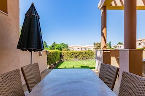 A patio with a table and chairs, a pergola, and a view of a garden and buildings. - 4-Bedroom Villa near the Beach – Casa Colina 2 (Albufeira)