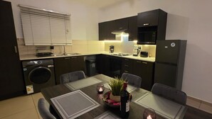 Cocina compacta con comedor, que incluye lavadora, pileta, estufa y refrigerador.