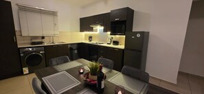 Eine kompakte Küche mit Essbereich, inklusive Waschmaschine, Spüle, Herd und Kühlschrank.