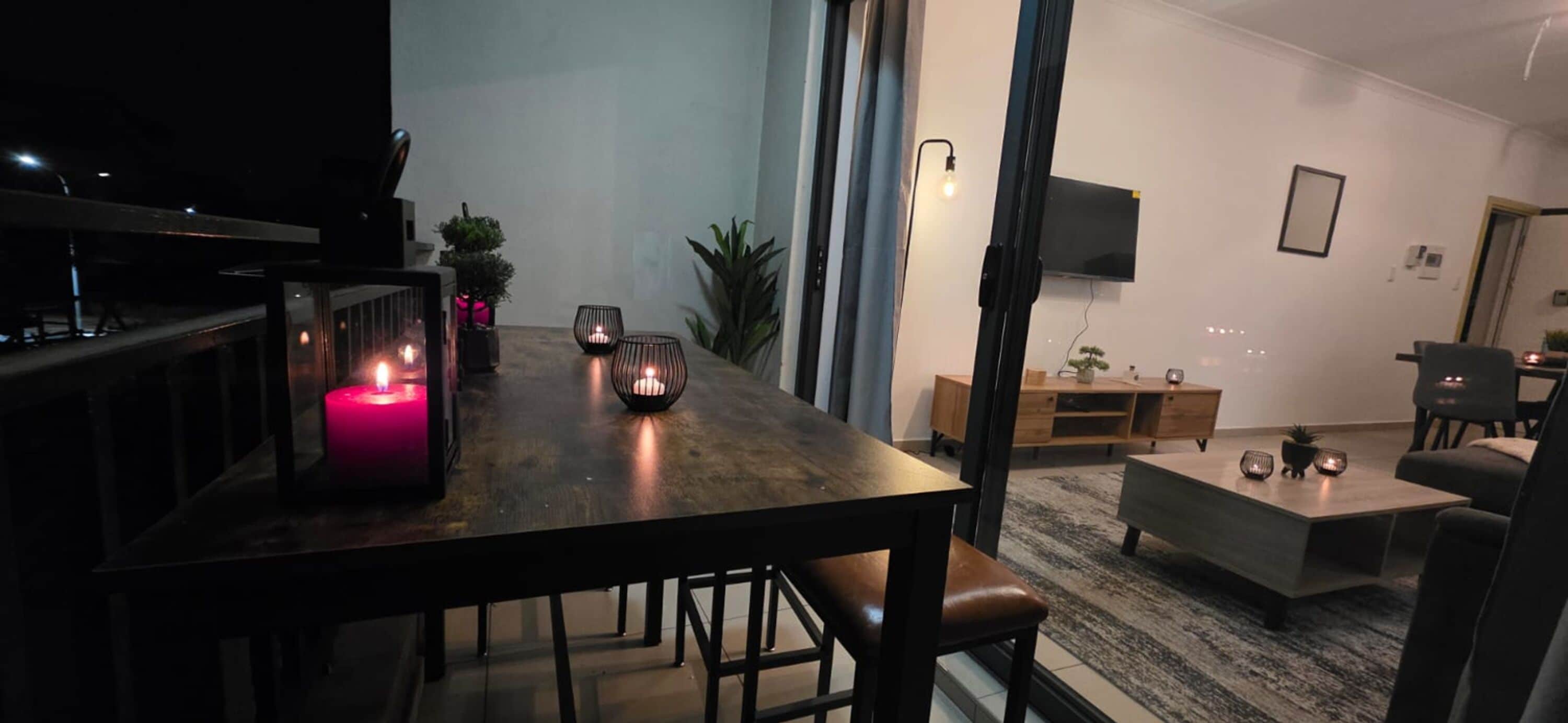 Una sala de estar moderna con una mesa de comedor de madera, un sofá y un televisor montado en la pared.