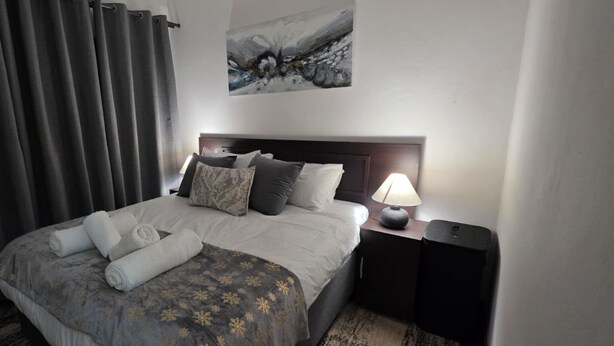 Una habitación de hotel con una cama, una mesita de noche, una lámpara y un cuadro en la pared.