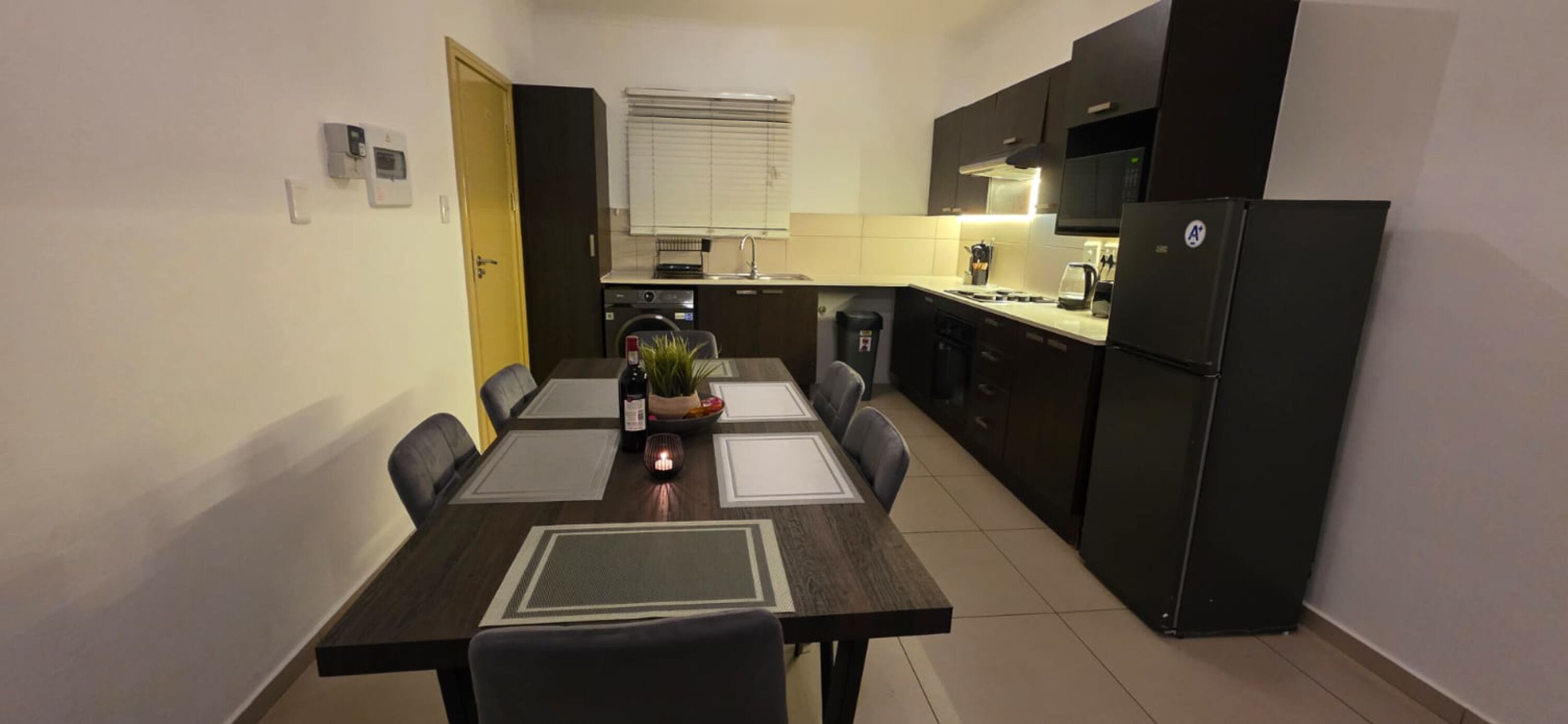 Une cuisine de taille réduite comprenant une table à manger, des chaises, un réfrigérateur et un four à micro-ondes.