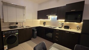Una cocina compacta con lavadora, microondas y un pequeño comedor.