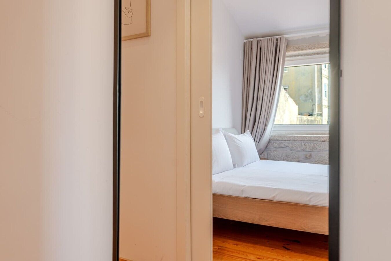 Un dormitorio con cama, ventana con cortinas y vistas al exterior.