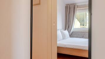 Un dormitorio con cama, ventana con cortinas y vistas al exterior.