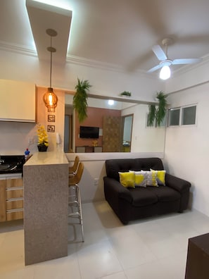 A modern living space with a kitchen island, seating area, and a ceiling fan. - 206 Versátil e Aconchegante (Belém)
