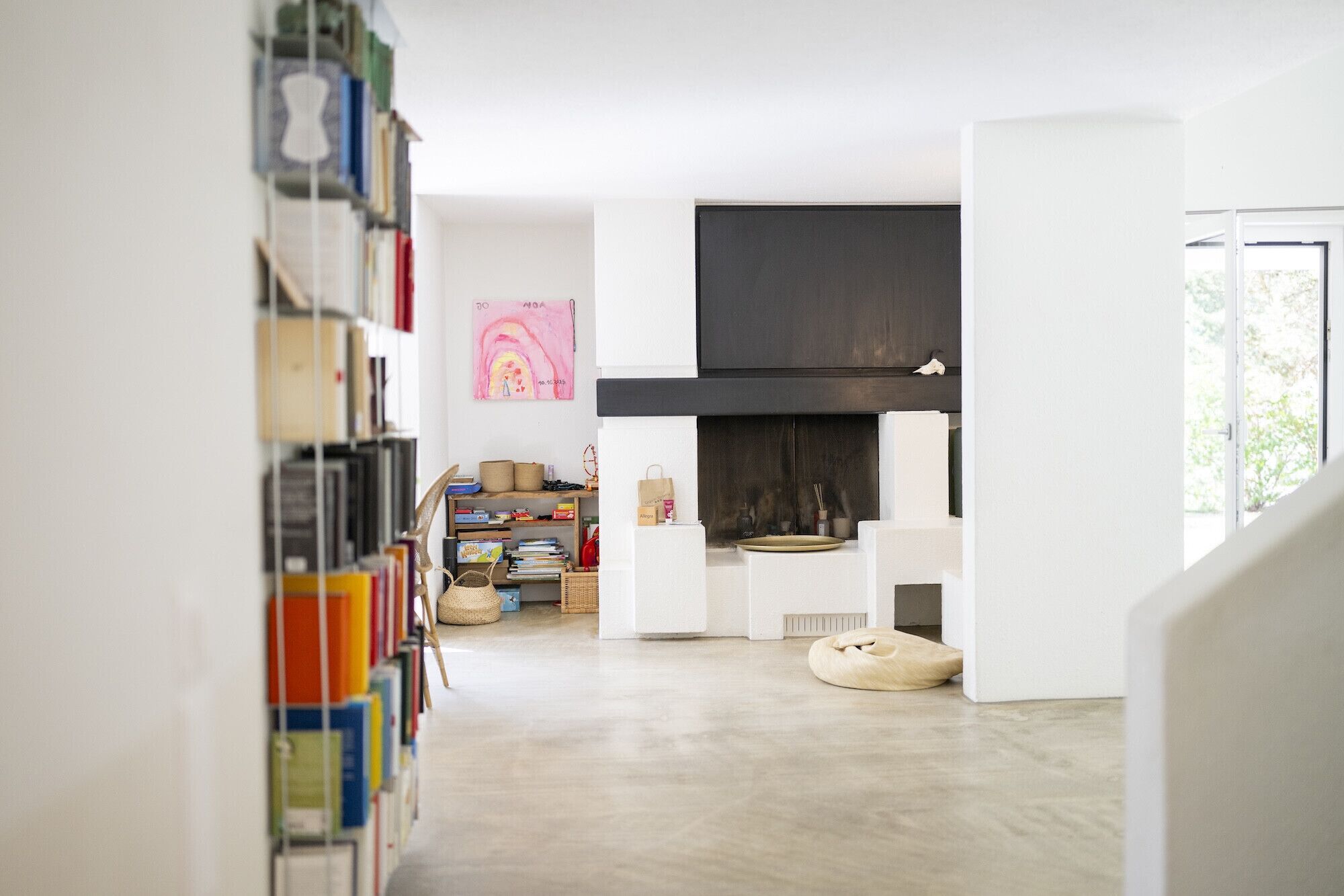 Ein modernes Interieur mit Kamin, Bücherregalen und freiem Blick ins Freie.