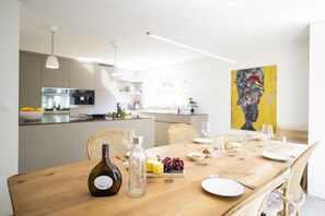 A dining area with a wooden table set for a meal, a bottle of wine, and a glass of water. - Chasa Val 739 - Spacious vacation home with a garden sauna and hot tub in Scuol (Scuol)