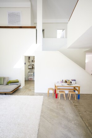 Ein modernes Interieur mit einem weißen Sofa, einem kleinen Holztisch mit Stühlen und einem weißen Teppich.