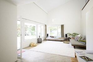 Um quarto espaçoso com uma cama grande, um sofá, uma mesa pequena e uma janela com vista para o exterior.