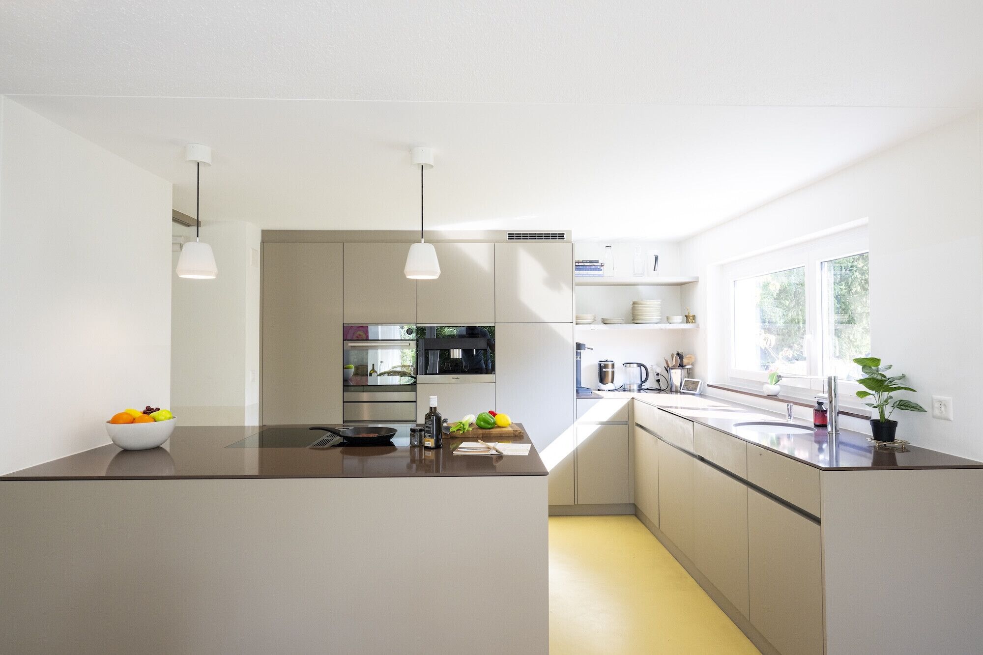 A modern kitchen with a central island, built-in appliances, and a window providing natural light.