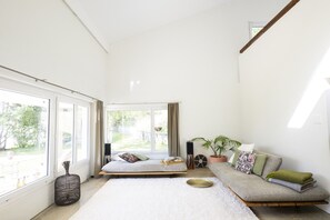 A spacious room with a large window, a sofa, a small table, and a potted plant. - Chasa Val 739 - Spacious vacation home with a garden sauna and hot tub in Scuol (Scuol)