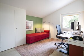 A compact room with a red sofa, a desk with a computer, and a window providing natural light. - Chasa Val 739 - Spacious vacation home with a garden sauna and hot tub in Scuol (Scuol)