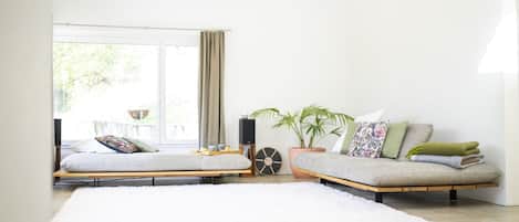 Uma sala de estar moderna com um conjunto de sofá, um tapete branco, uma planta em vaso e uma janela com cortinas.