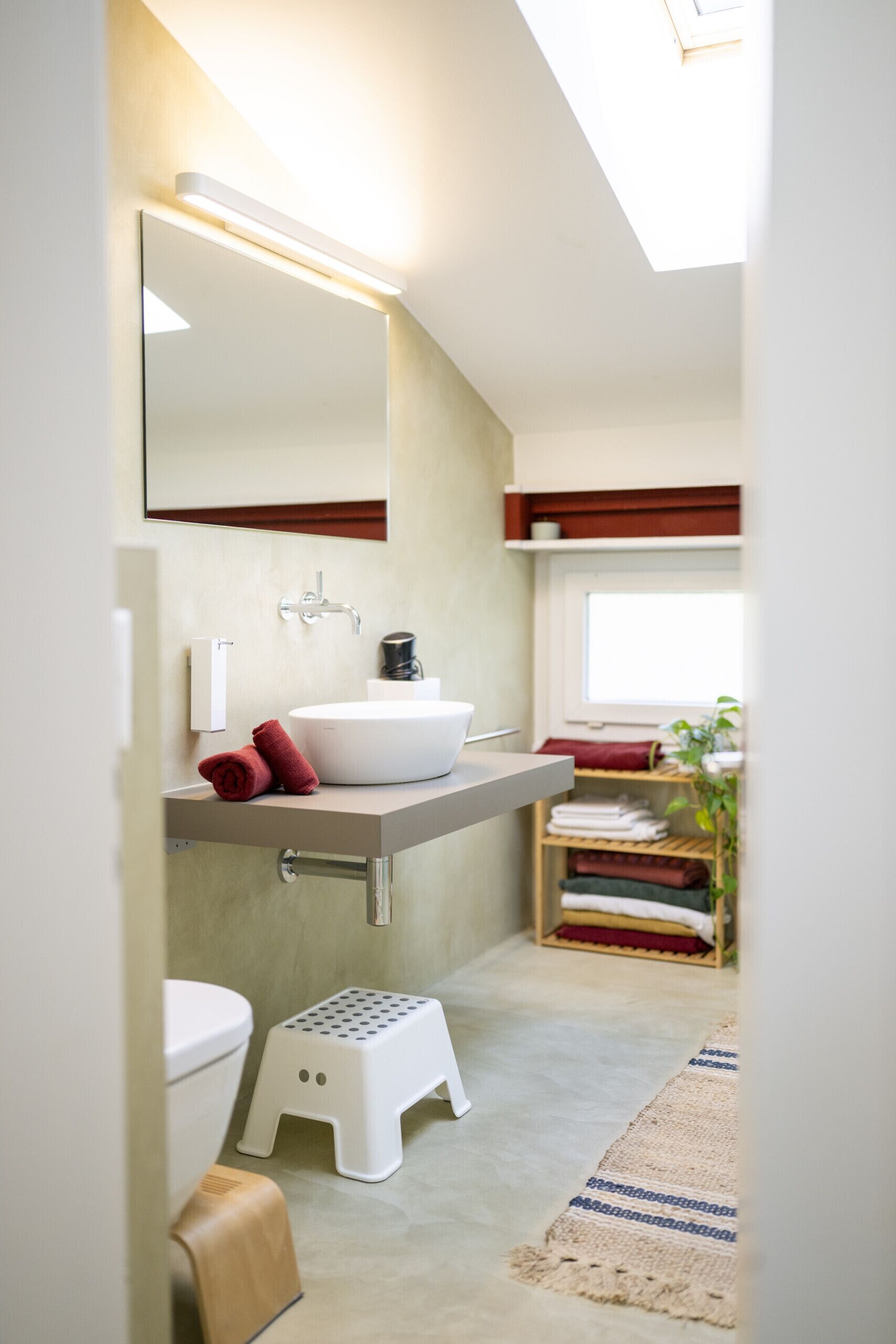 Een moderne badkamer met een witte wastafel, een spiegel en een handdoekrek.