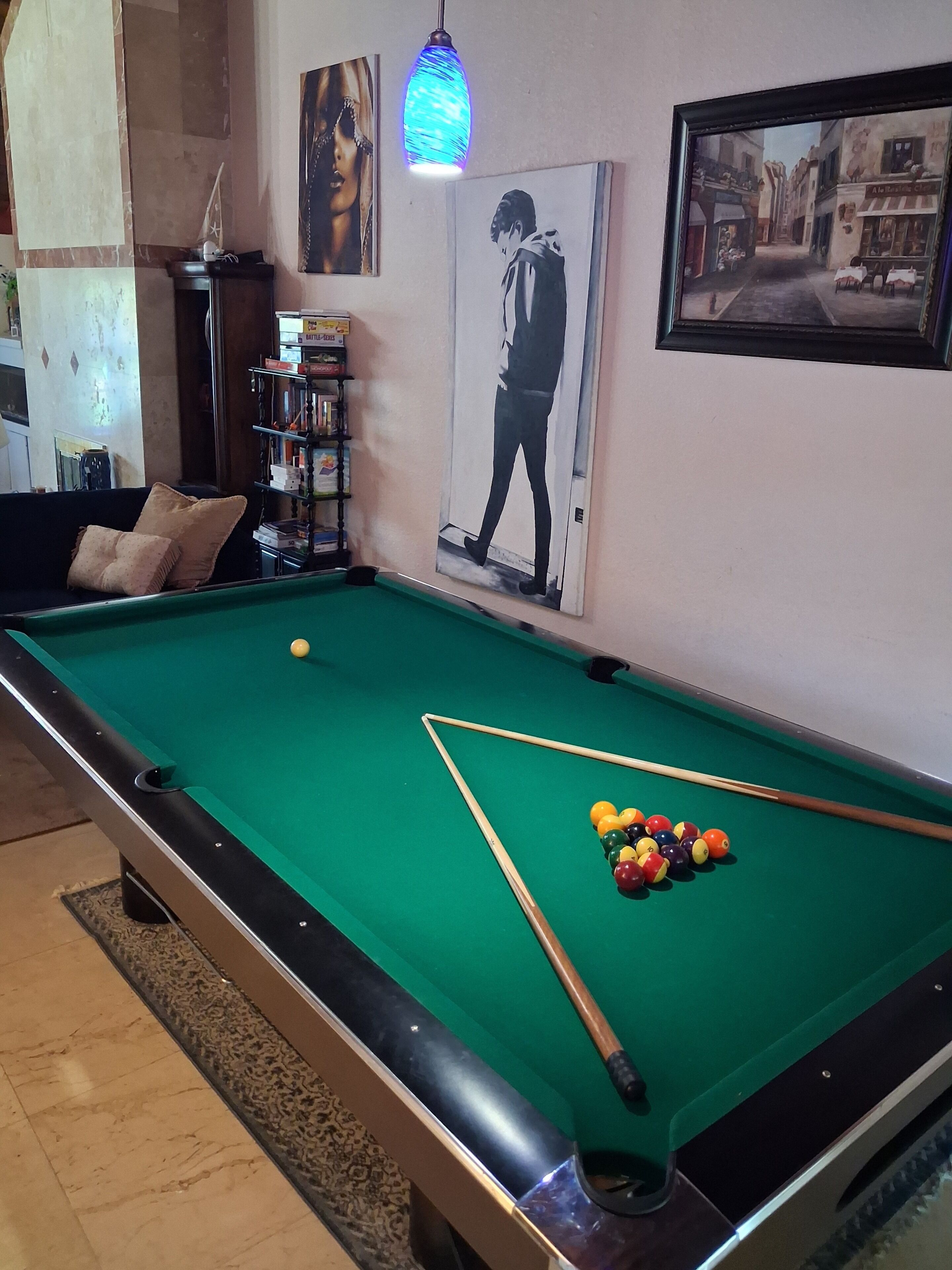 Une table de billard avec des billes, une queue de billard et un portrait encadré.