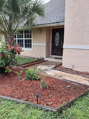 A house with a front yard, a palm tree, and a wooden deck.