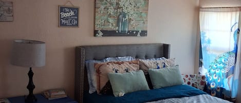 Une chambre à coucher avec un lit, une table de chevet, une lampe et des œuvres d’art murales.