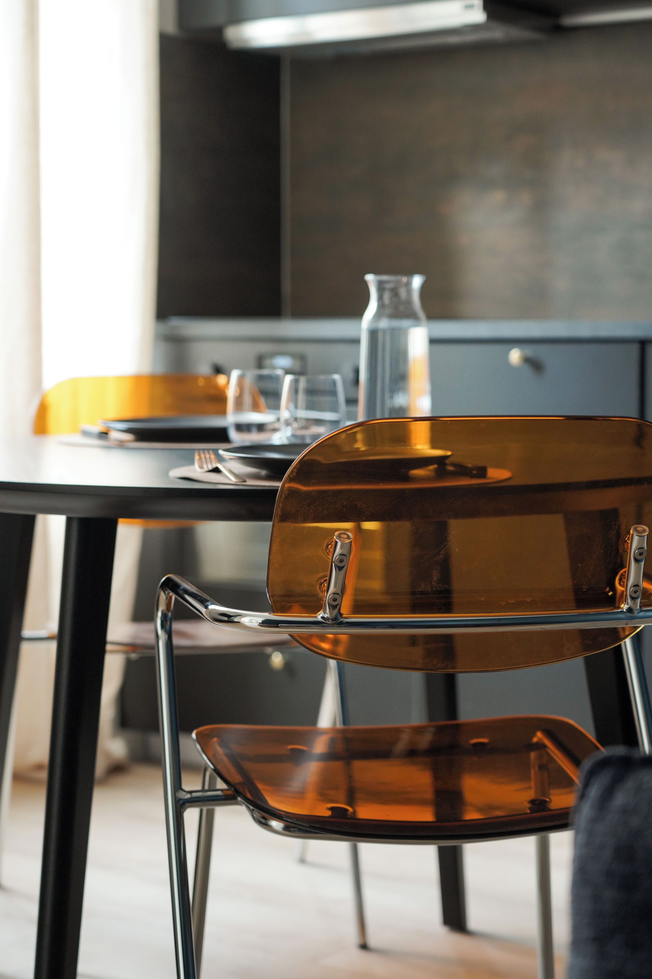 Cocina moderna con mesa, sillas y un jarrón.