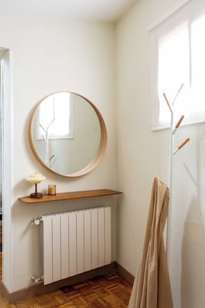 A bathroom with a wooden vanity, a round mirror, a radiator, and a towel rack. - Private and quiet on Cuesta de Santo Domingo, this three bedroom apartment sits in one of the best locations in Madrid, with the Royal Palace and Teatro Real just steps away and Puerta del Sol and Plaza Mayor an easy walk beyond. (MADRID)