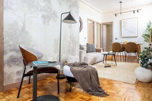 A modern living room with a sofa, a coffee table, a floor lamp, and a dining area with chairs and a table. - Private and quiet on Cuesta de Santo Domingo, this three bedroom apartment sits in one of the best locations in Madrid, with the Royal Palace and Teatro Real just steps away and Puerta del Sol and Plaza Mayor an easy walk beyond. (MADRID)