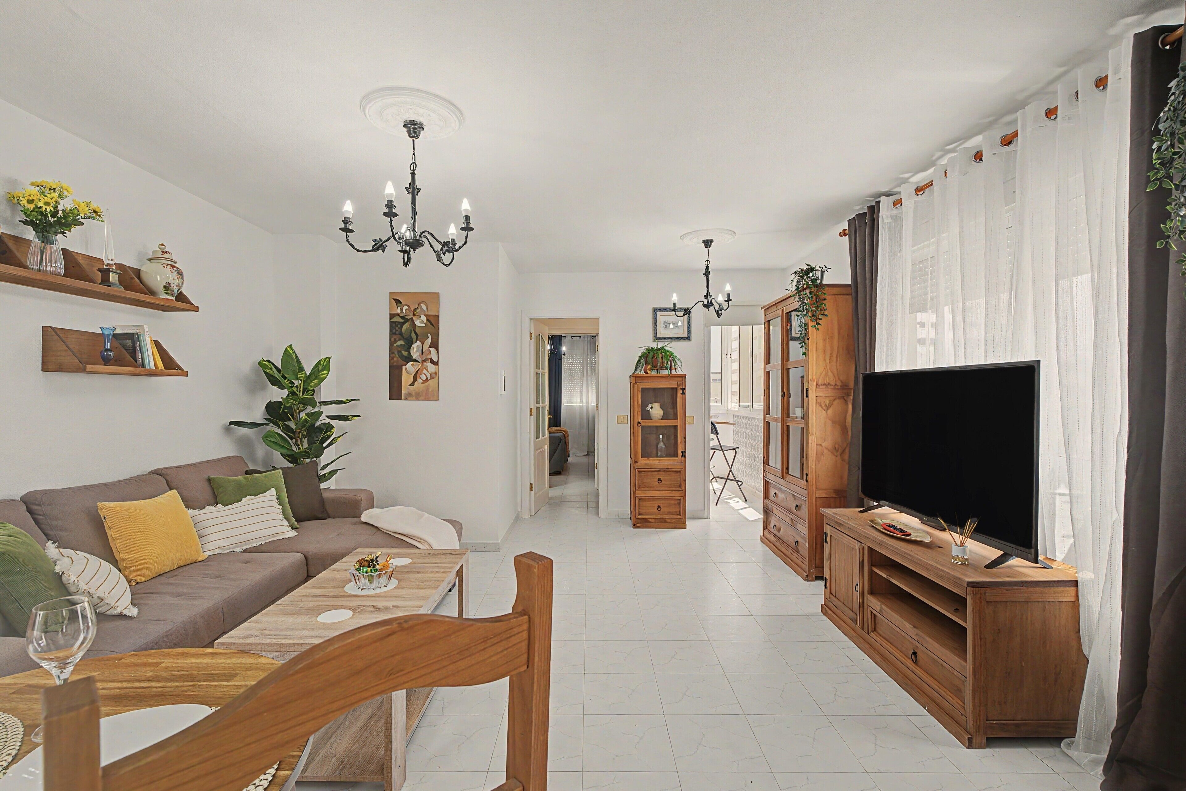 Una sala de estar moderna con sofá, mesa de centro, mueble para televisión y objetos decorativos.