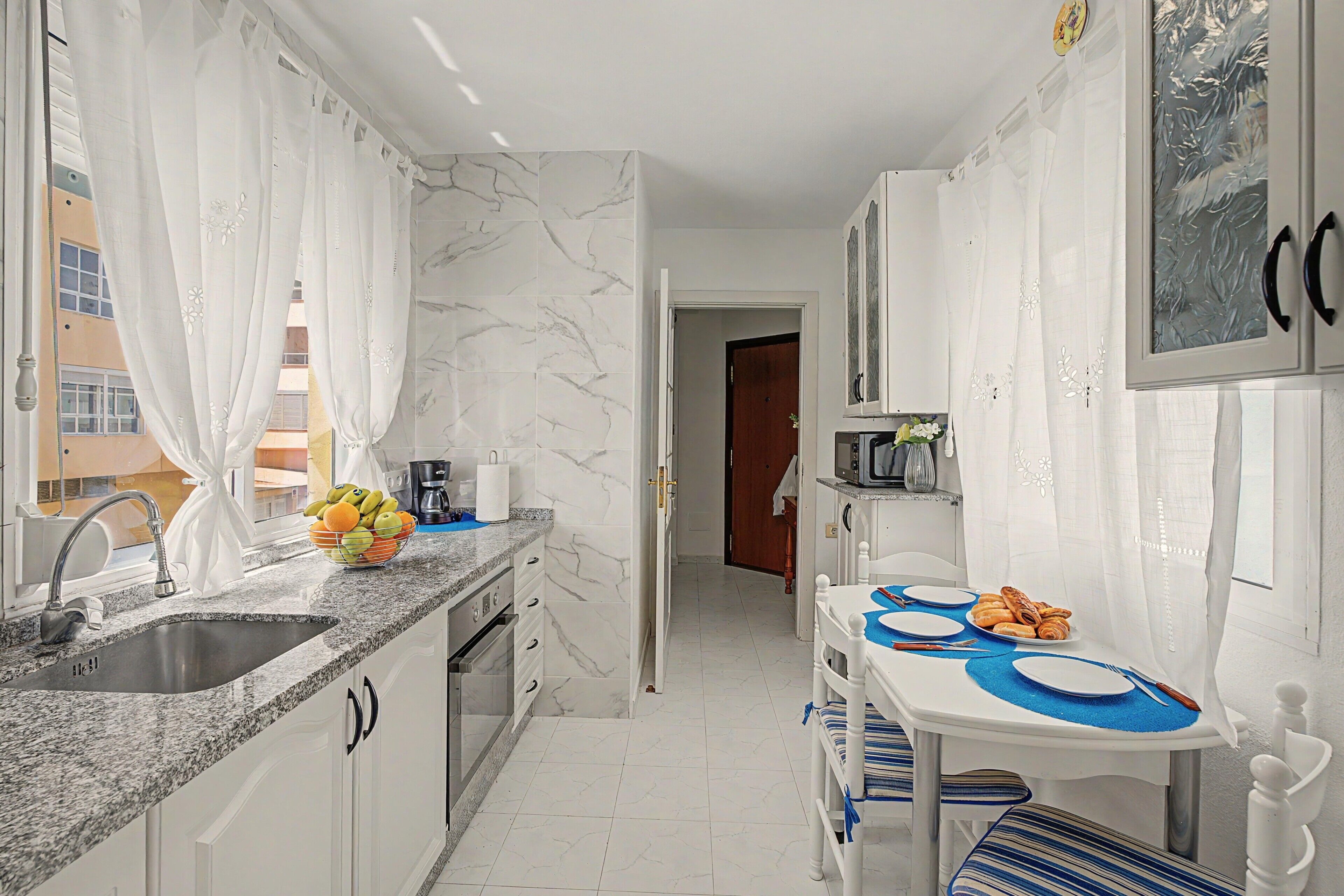 Cocina compacta con lavamanos, encimera y zona de comedor con mesa y sillas.