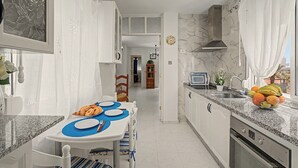 Une cuisine moderne avec un coin repas, des plans de travail en granit et une vue sur l’extérieur.