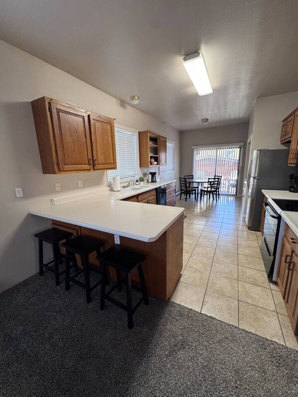 A kitchen with a central island, wooden cabinets, and a dining area with chairs.