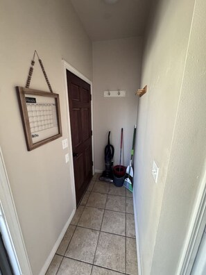 A hallway with a door, a calendar, and cleaning supplies.