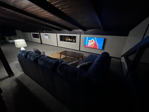 A living room with a dark blue sofa, a coffee table, and a flat-screen TV mounted on the wall.