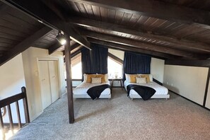 A room with two beds, a wooden ceiling, and a door.