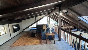 An attic room with a sloped ceiling, a sofa, a small table, and a rug.