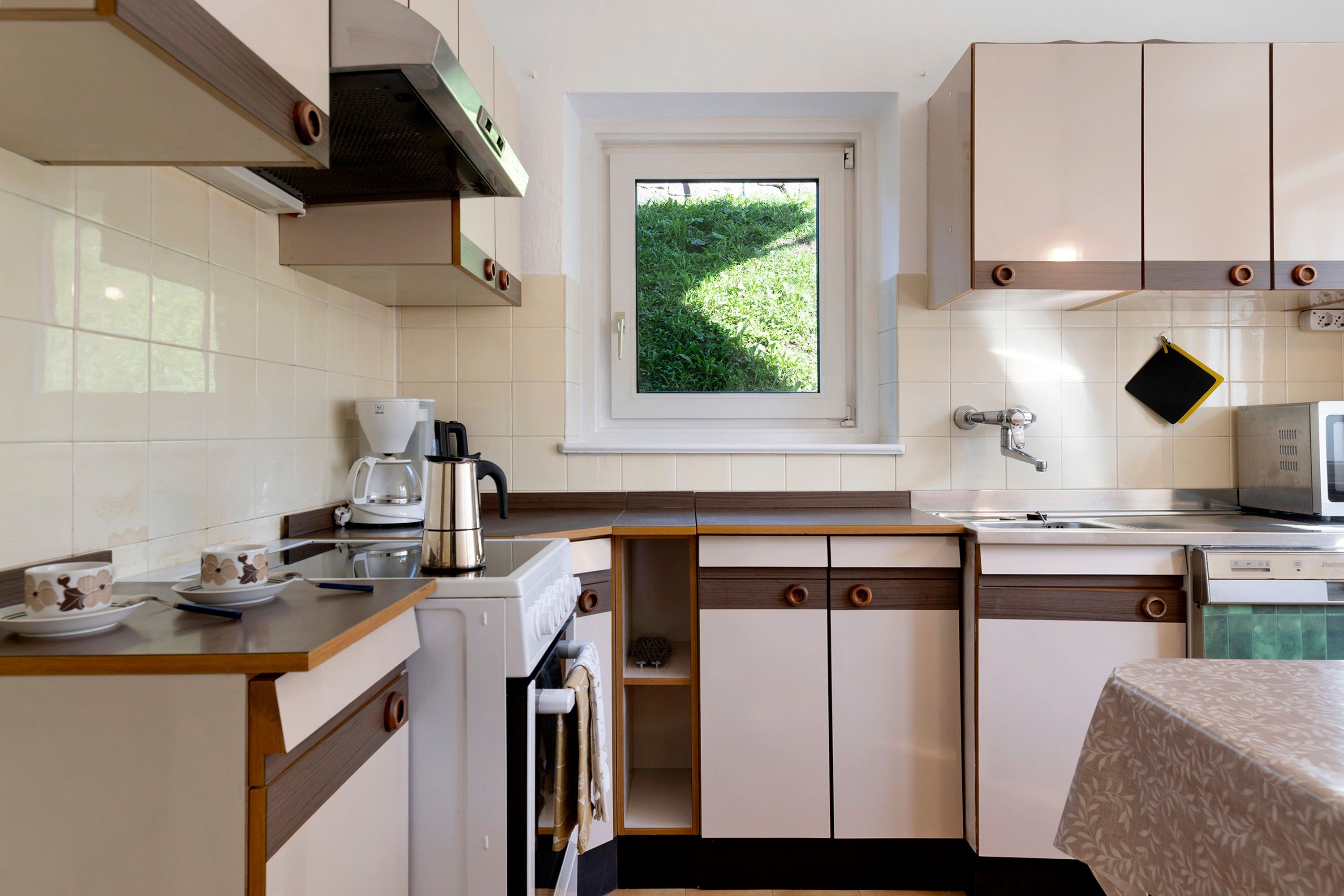Una cucina compatta con vista dalla finestra, una macchina da caffè e un forno a microonde.