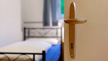 Une porte avec une poignée, un lit avec un matelas bleu et une tête de lit en métal.