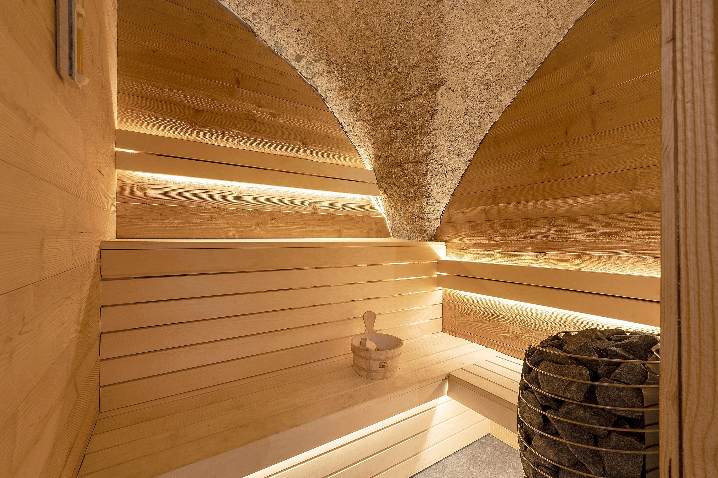 Una sauna in legno con pareti a listelli e una panca in pietra.