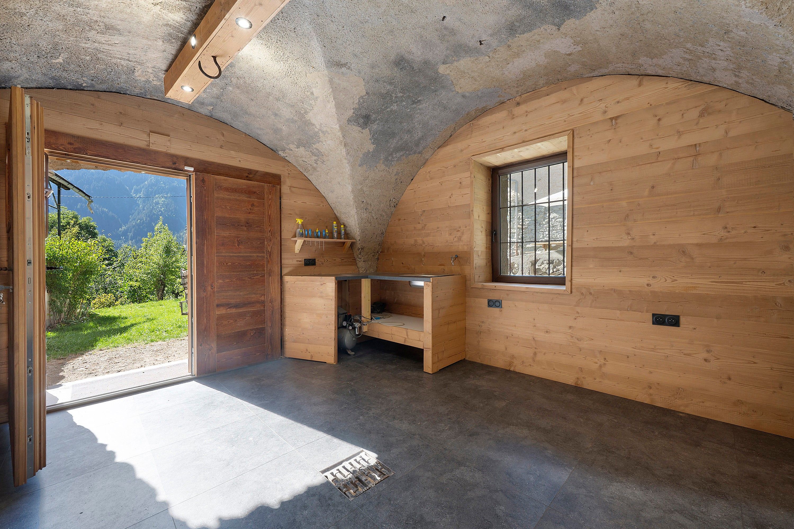 A compact room with wooden walls, a built-in bench, a window, and a door leading outside.