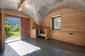 Habitación pequeña con paredes de madera, un banco integrado, una ventana y una puerta que da al exterior.